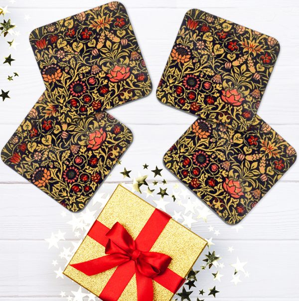 A set of 4 William Morris coasters with a gold gift box on table.